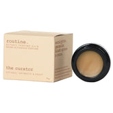Routine The Curator solid perfume - cream packaging box with botanical scent description and black jar showing smooth balm texture